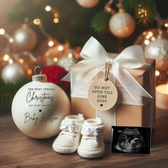 a baby's first christmas ornament and booties next to a gift box