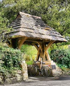 two bicycles are parked in front of a wooden gazebo surrounded by greenery and trees