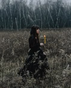 a woman sitting in a field holding a candle