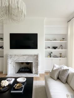 a living room with white furniture and a fireplace