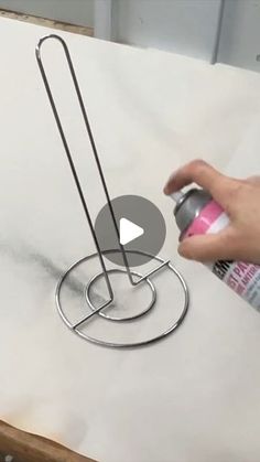 a person is using spray paint on a piece of paper with a metal holder attached to it