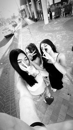 two young women standing next to each other on a brick sidewalk with their fingers in their mouths