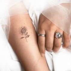 a woman's arm with a sunflower tattoo on her left hand and a diamond ring