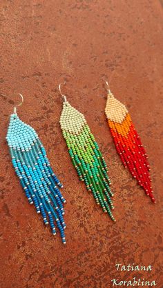 three pairs of beaded earrings sitting on top of a brown table next to each other