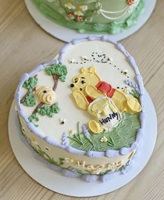 two winnie the pooh birthday cakes sitting on top of a wooden table next to each other