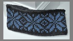 a blue and black knitted headband hanging from a door handle on a white surface