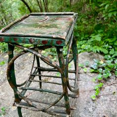 an old wooden table sitting on top of a rock covered in leaves and vines,