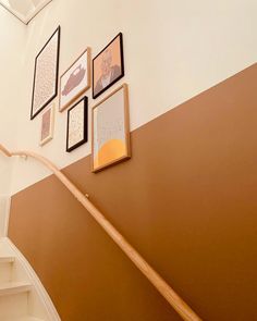 a staircase with pictures on the wall above it and a wooden hand rail in front