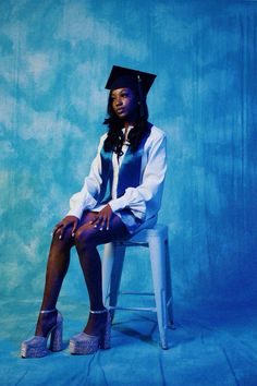 a woman sitting on top of a white chair wearing a graduation cap and dress shirt