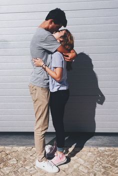 a man and woman embracing in front of a garage door