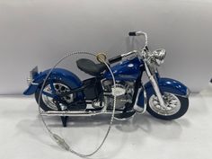 a blue toy motorcycle is shown on a white surface with a silver cable connected to it