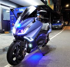 the motorcycle is parked on the side of the road near some cars at night time