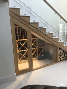 a living room filled with furniture and a wine rack under a stair case next to a glass door