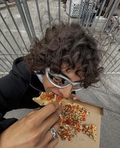 a woman eating a slice of pizza with goggles on