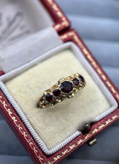 A beautiful 1970s vintage 9ct gold garnet ring! This unusual & charming piece features five round, sparkling garnets, each offering a glowing shade of red, with the largest gemstone sitting at the centre. The ring's setting has a unique design, comprising a luxurious thick rim of gold with a crinkle effect. Such a fantastic '70s piece of retro jewellery! This ring has been hallmarked by the London Assay Office and bears a date letter for 1979. It fits a UK size O (US size 7 1/4) and weighs 2.5 g 70s Rings, Gold Garnet Ring, 70s Retro Style, Retro Jewelry, 70s Retro, Garnet Rings, Retro Stil, Vintage Jewellery, Shades Of Red