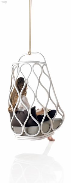 a woman is sitting in a chair that looks like a birdcage hanging from the ceiling