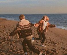 two people are running on the beach near the water