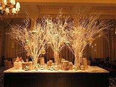 there are many branches with ornaments on them in the center of this table, along with other decorations