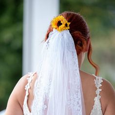 the back of a bride's dress with a sunflower in her hair and veil