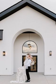 a bride and groom standing in front of a white building with black trimmings