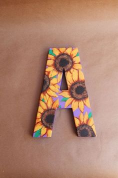 the letter a is decorated with sunflowers on a brown paper background and placed in front of it