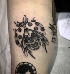 a ladybug and skull tattoo on the leg