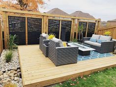 a patio with couches, tables and chairs next to a wooden deck in the grass