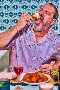 a man eating food at a table with two glasses of wine in front of him