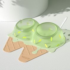 two green cups sitting on top of each other next to a white cup with yellow sprinkles