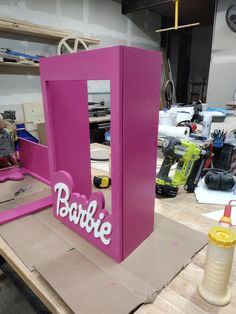 a pink box with the word barbie on it sitting on top of a workbench