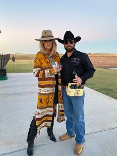 a man and woman standing next to each other wearing cowboy hats, scarves and boots