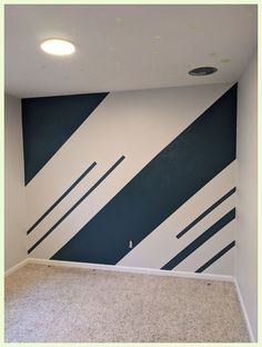 an empty room with blue and white stripes painted on the wall, carpeted floor