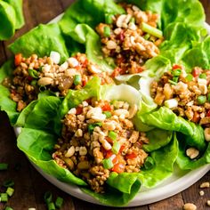 lettuce wraps filled with meat and vegetables on a white plate next to sliced limes