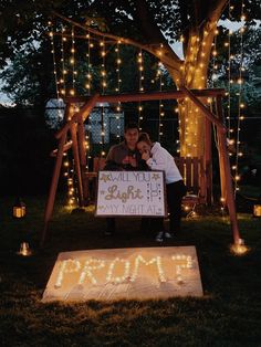 a man and woman standing in front of a sign that says i love you at night