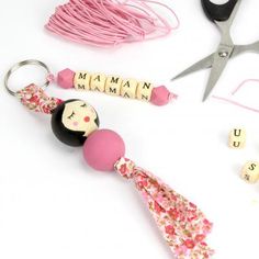 a pair of scissors, bead and keychain on a white table with beads