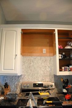 a stove top oven sitting inside of a kitchen next to a microwave and cupboards