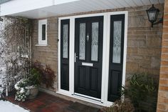 a black and white front door on a brick house with potted plants next to it