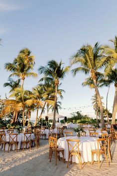 tables and chairs set up on the beach with palm trees