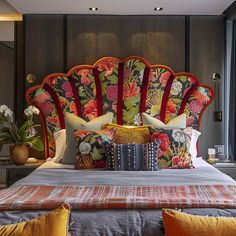 a bed with an ornate headboard and colorful pillows on top of it, along with other decorative items