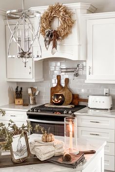 a kitchen with white cupboards and an oven in the center is decorated for fall