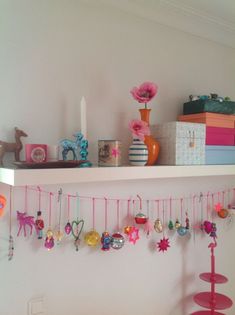 a shelf filled with lots of ornaments on top of a white wall next to a bed