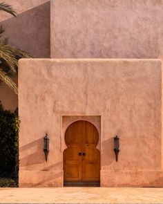 an entrance to a building with a wooden door and two lights on the outside wall