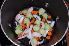 onions, carrots and celery being cooked in a wok on the stove