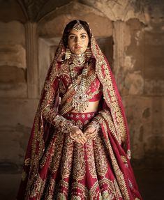 a woman in a red and gold bridal gown standing with her hands on her hips