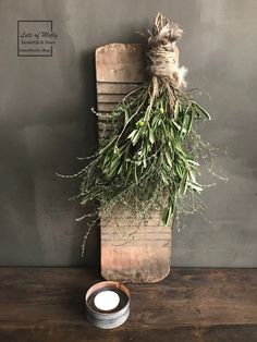 a wooden cutting board with some herbs on it and a candle in front of it