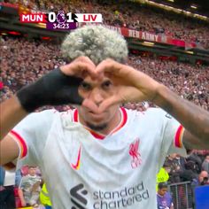 a man making a heart sign with his hands in front of him at a soccer game