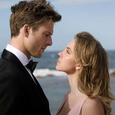 a man and woman standing next to each other near the ocean