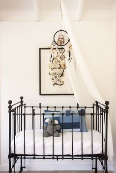 a black iron bed frame with white sheets and pillows in a small room that has a chandelier hanging from the ceiling