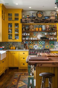 a kitchen with yellow cabinets and lots of plates on the shelves above the stove top