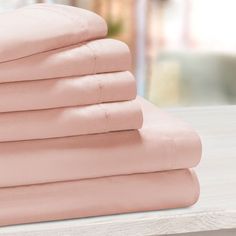 a stack of pink sheets sitting on top of a wooden table